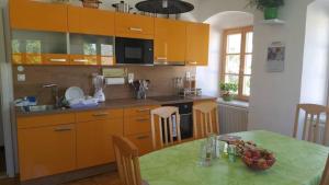 a kitchen with orange cabinets and a table with a bowl of fruit at Ferienhaus für 10 Personen in Ulrichsberg, Oberösterreich Mühlviertel in Ulrichsberg