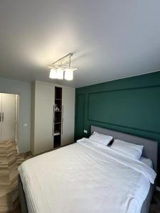 a bedroom with a large white bed with a green wall at Central Park Apartment in Chişinău