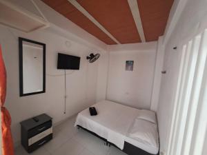 Habitación blanca pequeña con cama y TV en HOSTAL LOS CAMINANTES, en Villavieja