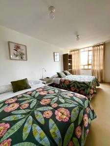 a hotel room with two beds with a floral bedspread at El Huerto Hostel in Ica