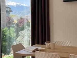 a table with two cups and a book and a window at Bernina Suite 2 - vicino al Bernina Express in Tirano