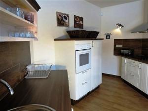 una cucina con armadi bianchi e forno bianco di Ferienhaus für 15 Personen in Madrzechowo, Pommern Kaschubische Seen 