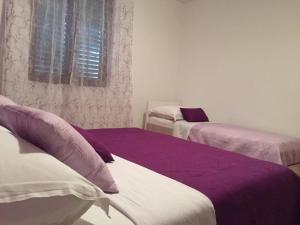 um quarto com 2 camas com lençóis roxos e brancos em Studio für 10 Personen in Lozice auf Vir, Dalmatien Inseln vor Zadar em Lozice