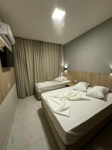 two beds in a hotel room with at Hotel Minorus in Aparecida