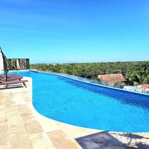 トゥルムにあるLuxury Condo in the Heart of Tulum!!の青い水とベンチ付きのスイミングプール
