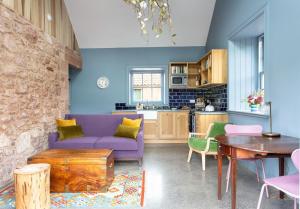 uma sala de estar com um sofá roxo e uma mesa em Ploughman's Bothy at Papple Steading em East Linton