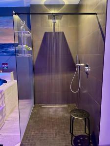 a bathroom with a shower with a stool in it at Le Moulin de Bury, Maison de campagne au bord de la rivière à 13 kms au Sud de Rennes in Chavagne