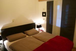 una camera da letto con un letto con una coperta rossa e cuscini di Ferienhaus Sefi a Lechbruck