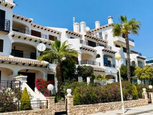 un grand bâtiment blanc avec des palmiers et des fleurs dans l'établissement Casa Refa en Cabo Roig, à Orihuela Costa