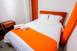 Una cama naranja y blanca con dos toallas. en La Villa de Roel en Ayacucho