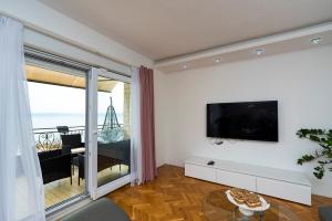 a living room with a flat screen tv on a wall at M&M Pelivan apartment in Kaštela