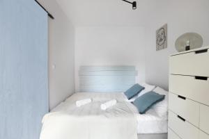 een witte slaapkamer met een bed met blauwe kussens bij Malila Premium Apartments Cracow City Center Pawia 34 in Krakau