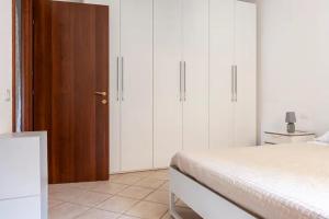 a white bedroom with white cabinets and a bed at Casa Nadia - Incantevole appartamento con giardino in Guardistallo