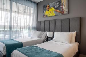 2 camas en una habitación de hotel con un cuadro en la pared en Tres habitaciones - Vista al Mar en Cartagena de Indias