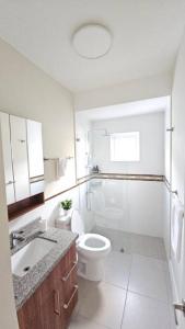 a white bathroom with a toilet and a sink at Ocean Blue Villa in Lucea in Point +11 photos