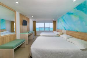 2 Betten in einem Hotelzimmer mit einem großen Fenster in der Unterkunft Hotel Bahia Sardina in San Andrés