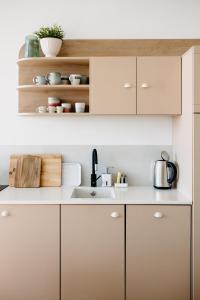 a kitchen with white cabinets and a sink at SUQO vendégház in Sukoró