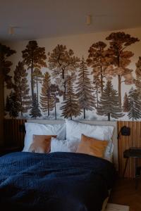 a bedroom with a bed with a forest mural on the wall at SUQO vendégház in Sukoró