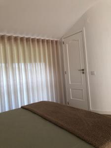 um quarto com uma porta e uma janela com cortinas em Sobreiro Valley - Casa Isabel em Vieira do Minho