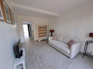 a living room with a white couch and a tv at Gîte cosy et tout équipé "Une cabane en Luberon" 44 m2 avec jardin in Pertuis