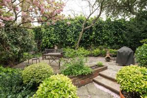 einen Garten mit einer Bank und einem Tisch und einigen Büschen in der Unterkunft Elegant 2-Bed Duplex with Patio nr Battersea Park in London