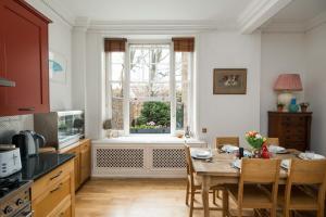 a kitchen with a table with chairs and a window at Elegant 2-Bed Duplex with Patio nr Battersea Park in London