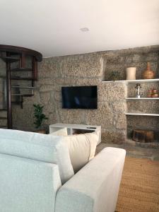 a living room with a couch and a tv on a stone wall at Sobreiro Valley - Casa Isabel in Vieira do Minho