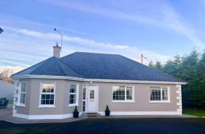 a white house with a black roof at The Lodge Self Catering in Castlerea