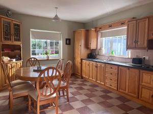 una cocina con armarios de madera, mesa y sillas en The Lodge Self Catering en Castlerea
