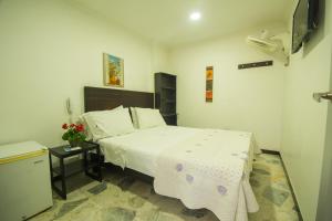 a small bedroom with a bed and a night stand at Hotel villeta suite in Villeta