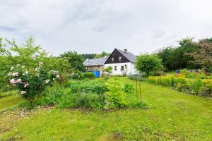 einen Hof mit einem Haus und einem Garten mit Blumen in der Unterkunft Poklidná Chalupa in Klenovice