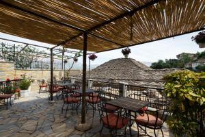 patio con tavoli e sedie sotto un tetto di Hotel Pashai a Gjirokastër