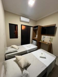 a hotel room with two beds and a flat screen tv at Casa Lua Flat in Brumadinho