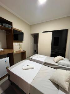 a hotel room with two beds and a flat screen tv at Casa Lua Flat in Brumadinho