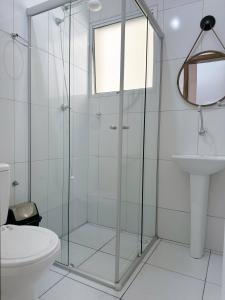 W łazience znajduje się szklana kabina prysznicowa, toaleta i umywalka. w obiekcie Apartamento Sun Way Ubatuba- com piscina, churrasqueira e play ground w mieście Ubatuba