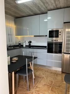a kitchen with white cabinets and a black table and chairs at Success House in Calheta