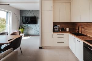 a kitchen with white cabinets and a table at Apartamenty nad Baryczą in Milicz