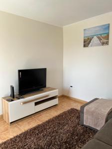 a living room with a flat screen tv on a cabinet at Success House in Calheta