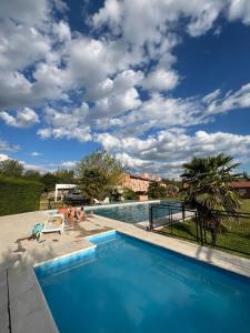 a blue swimming pool with a cloudy sky at Hotel Aimara in Mina Clavero