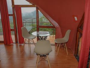 mesa y sillas en una habitación con ventana en GLAMPING MINDO SUYANA en Mindo