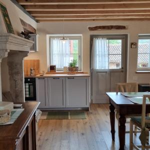 eine Küche mit weißen Schränken, einem Tisch und Fenstern in der Unterkunft Casa Gildo 1828 in Valdagno