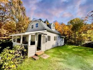 a small white house on a green lawn at Jewel Brook Cottage in Ludlow
