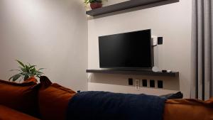 a living room with a couch and a flat screen tv at Apartamento Terracota in Piumhi