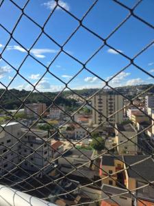 a view of a city through a chain link fence at Hospedagem Flat verde Sul de Minas in Caxambu
