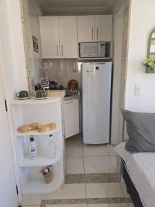 una piccola cucina con frigorifero bianco e armadietti bianchi di Hospedagem Flat verde Sul de Minas a Caxambu
