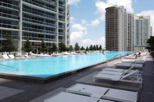 a large swimming pool with lounge chairs and buildings at Stunning Brickell Luxury Condo in Miami