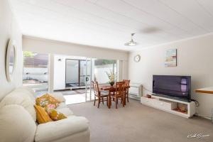 a living room with a couch and a tv and a table at A modern 2 bedroom with private backyard, kitchen. in Lower Hutt