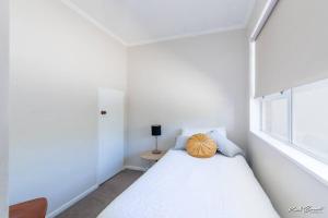 a white room with a bed with a pillow on it at A modern 2 bedroom with private backyard, kitchen. in Lower Hutt
