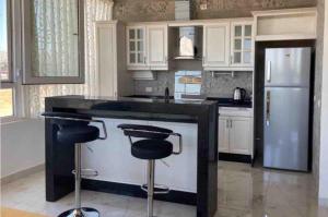 a kitchen with a black counter and stools at 1BR-Deir Gbar rooftop in Amman
