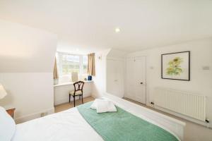 a white bedroom with a green rug on a bed at Westerpark Countryside Cottage in Huntly